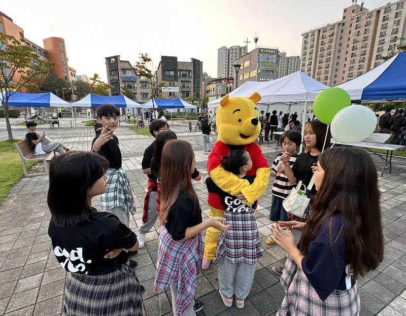 천막 부스가 늘어선 축제 광장에 모인 아이들과 인형 탈