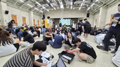 넓은 강당에 둘러앉아 활동하는 캠프 참가자들