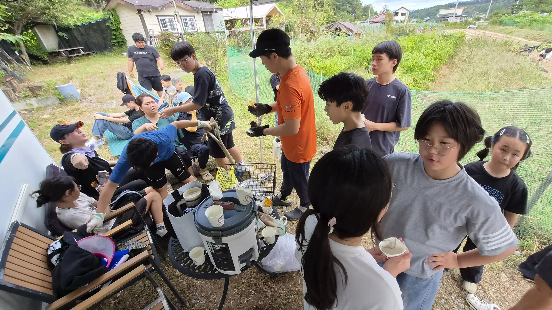 야외에서 음식을 나누며 이야기하는 청소년과 어른들