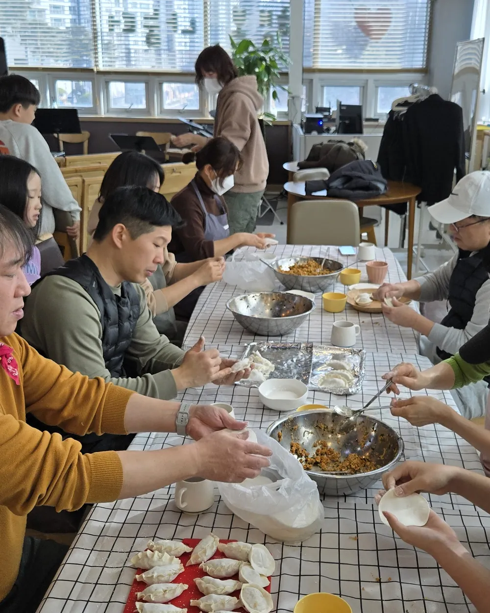 긴 테이블에 둘러앉아 함께 음식을 만드는 교인들