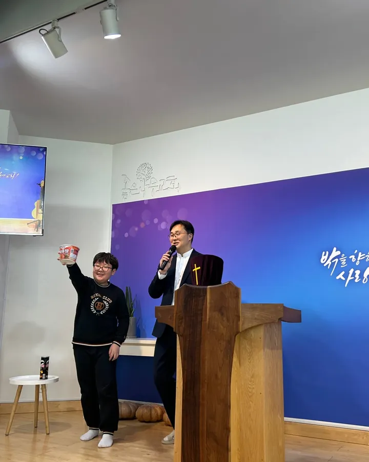 파란 배경막 앞 강대상에서 설교하는 목사