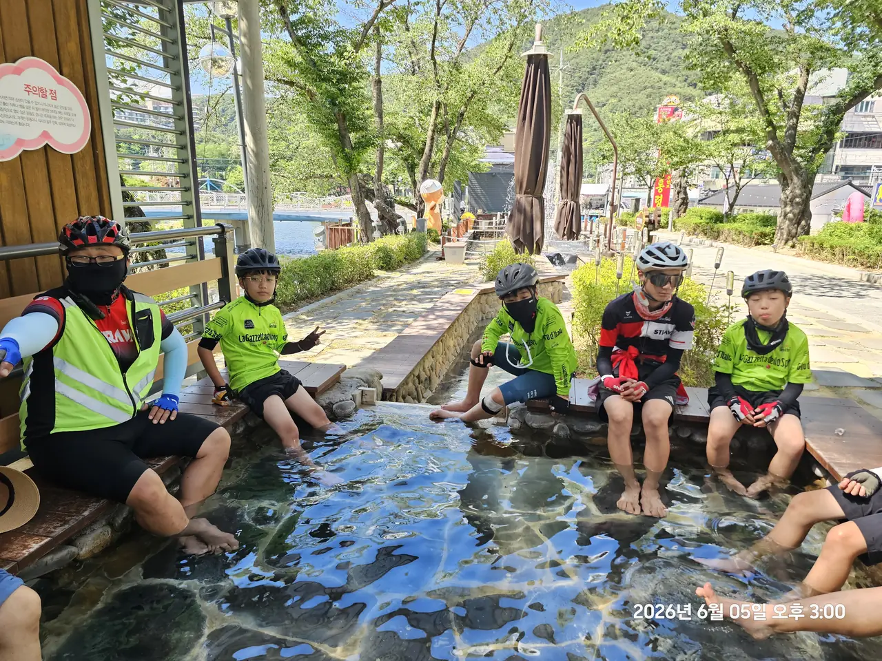 계곡물에 발을 담그고 쉬는 헬멧 쓴 청소년 라이더들