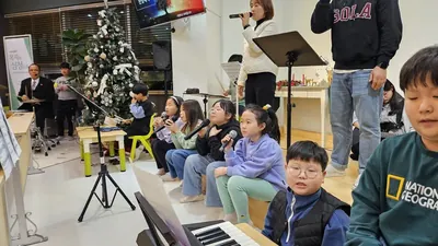 성탄 트리 옆에서 노래 순서를 기다리며 앉아 있는 아이들