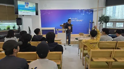 목재 장의자와 파란 배경막의 앞쪽이 보이는 예배 공간 내부, 특강을 듣는 사람들