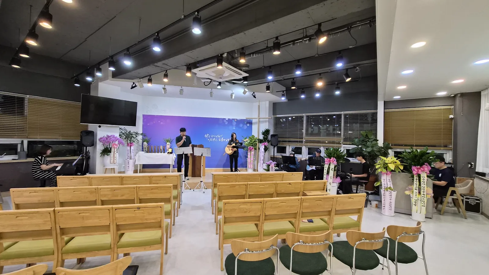 꽃 화분이 놓인 앞쪽과 긴 의자가 보이는 예배 공간